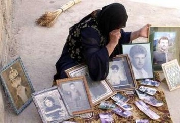 Írösk kona með ljósmyndir af ættingjum sem Saddam lét myrða